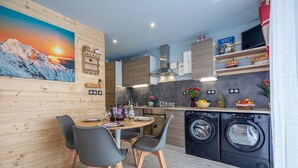 Eine moderne Küche mit Holzausstattung, ein Essbereich mit Tisch und Stühlen sowie eine Waschmaschine.