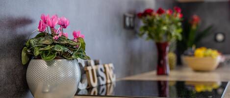 Een moderne keuken met een glanzend aanrecht, een potplant met roze bloemen en een decoratief bord met de tekst