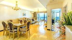 A spacious living area with a dining table, chairs, sofas, and a chandelier.