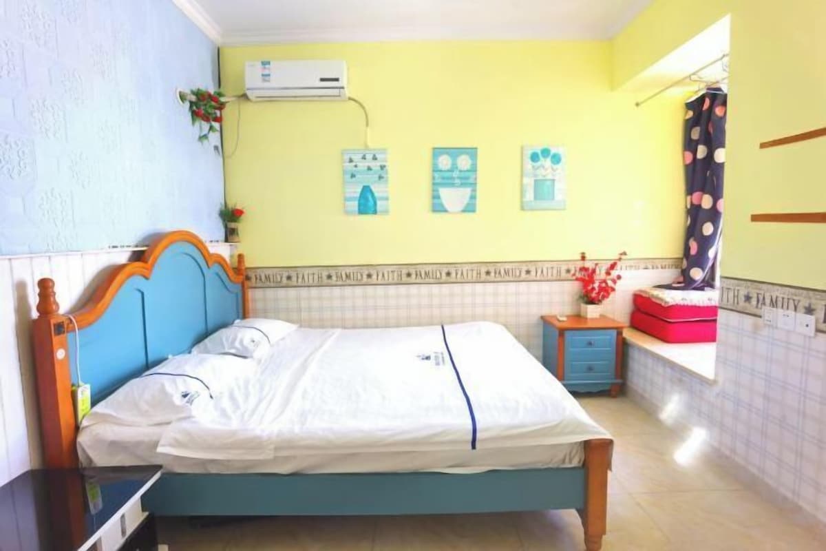 Un dormitorio con cama, una mesita de noche, una ventana con cortinas y un aire acondicionado instalado en la pared.