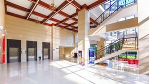 A spacious lobby with a high ceiling, multiple doors, a staircase, and a glass railing.