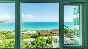 A view through a window of a coastal area with buildings, greenery, and the ocean.