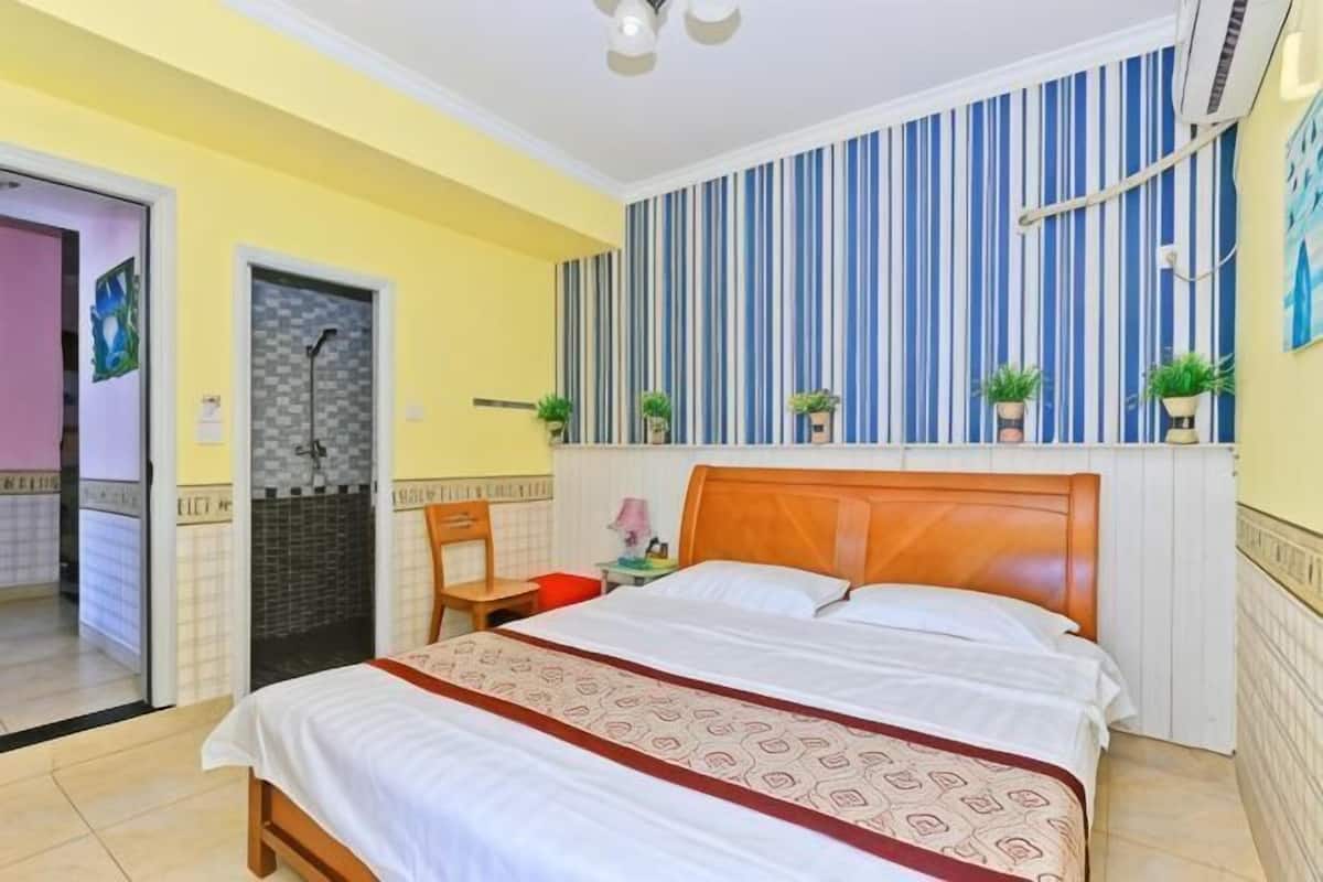 Een slaapkamer met een bed, een douche, een stoel en een gestreepte wand.