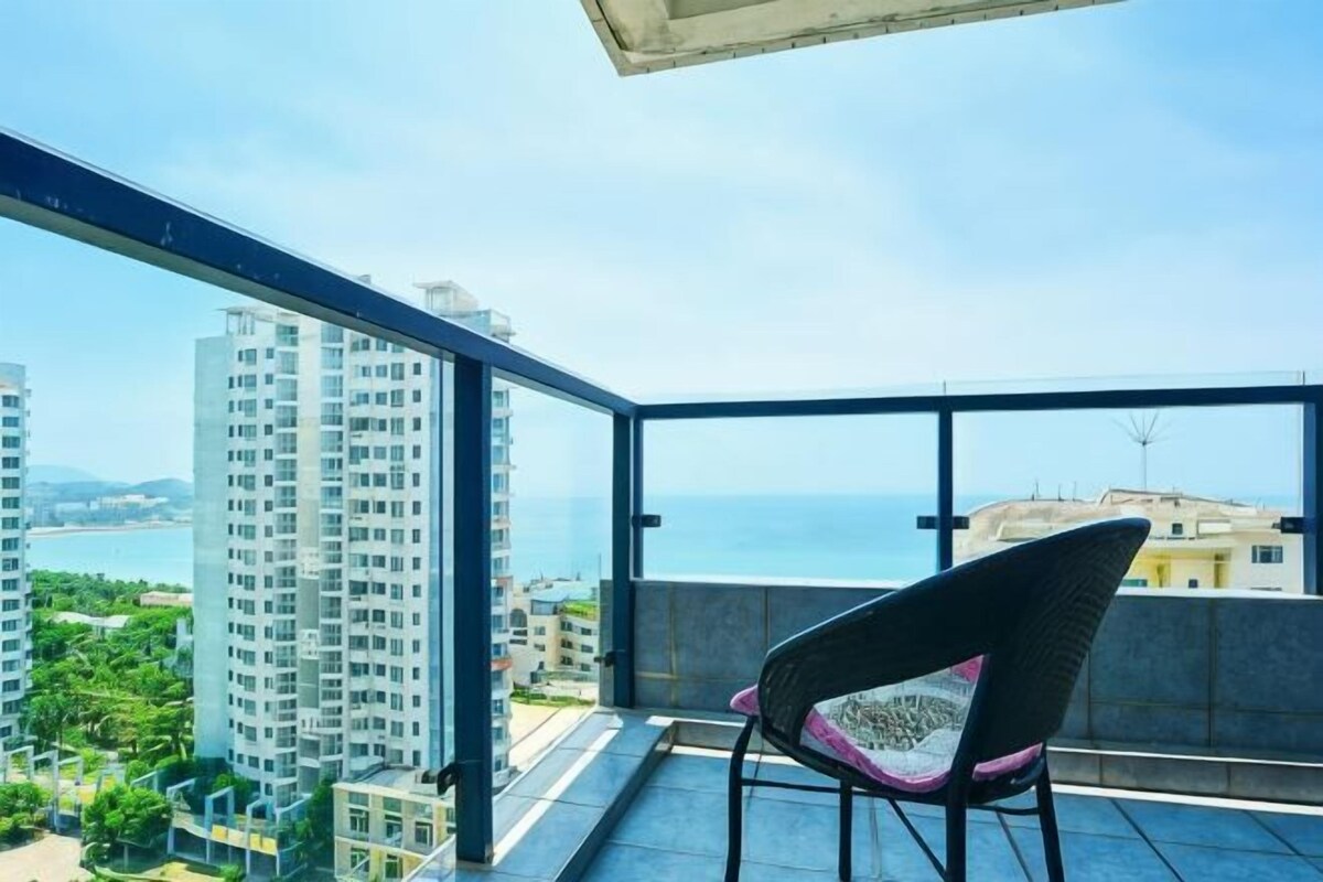 Un balcón con una silla, vista al mar y edificios altos.