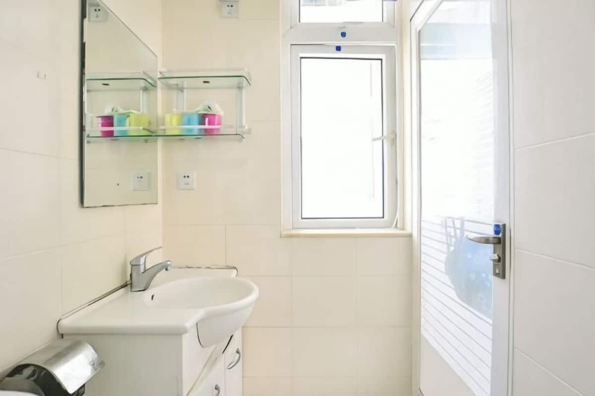 Een badkamer met een wastafel, spiegel en raam.
