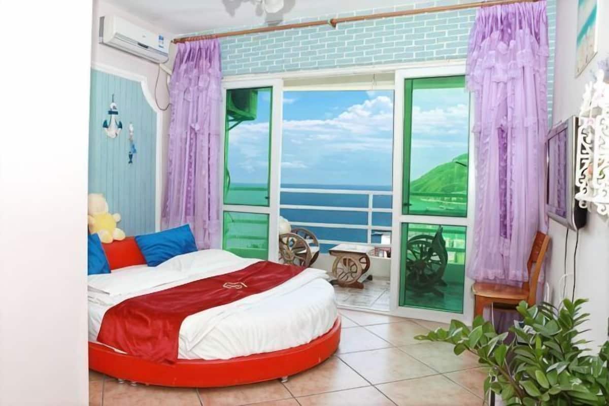 Een slaapkamer met een bed, een raam met uitzicht, een stoel en een plant.