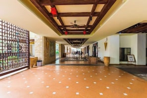 A corridor with a tiled floor, wooden ceiling beams, and a view of the outside.