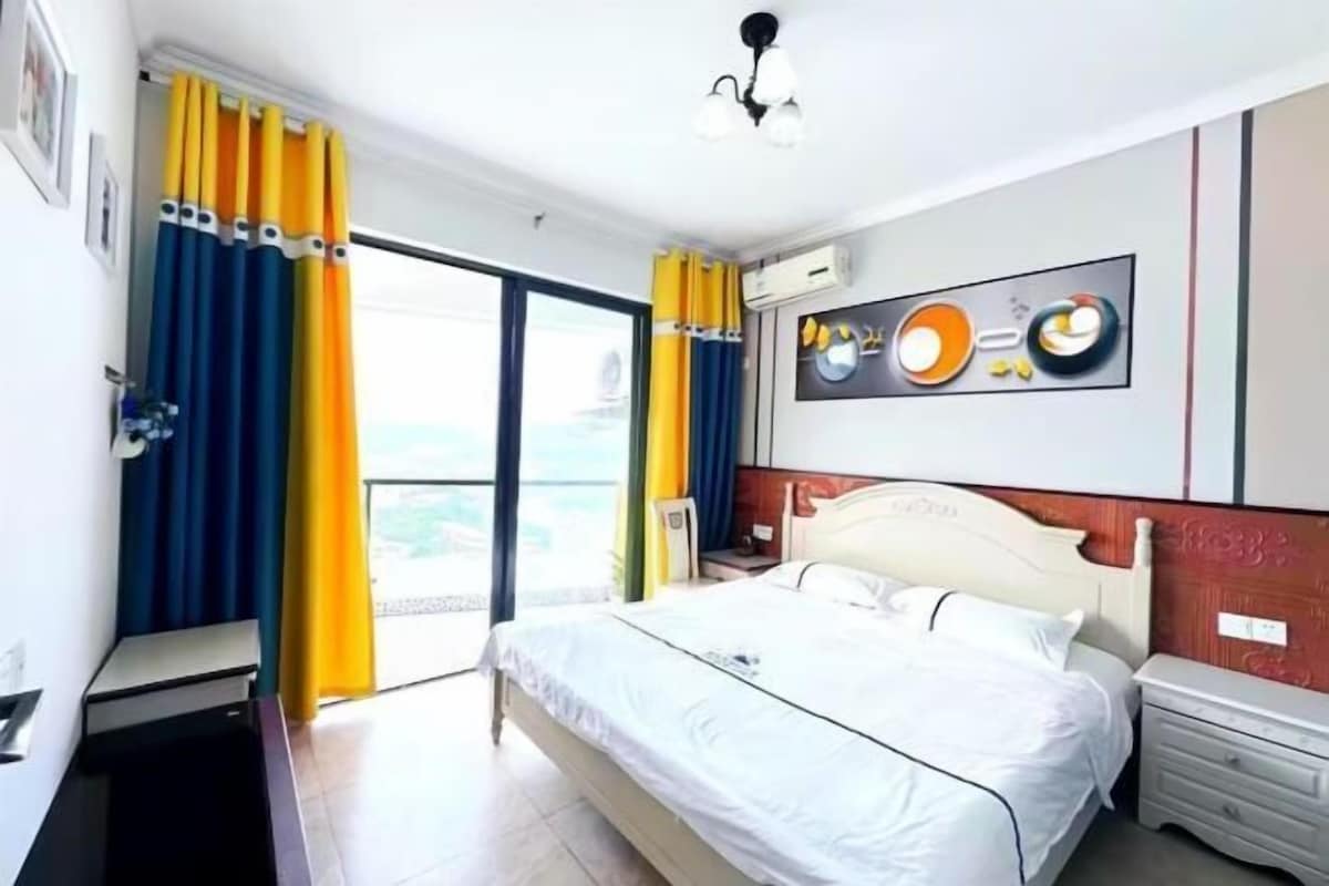 Habitación de hotel con una cama, una mesita de noche, aire acondicionado de pared y vistas a través de un ventanal.