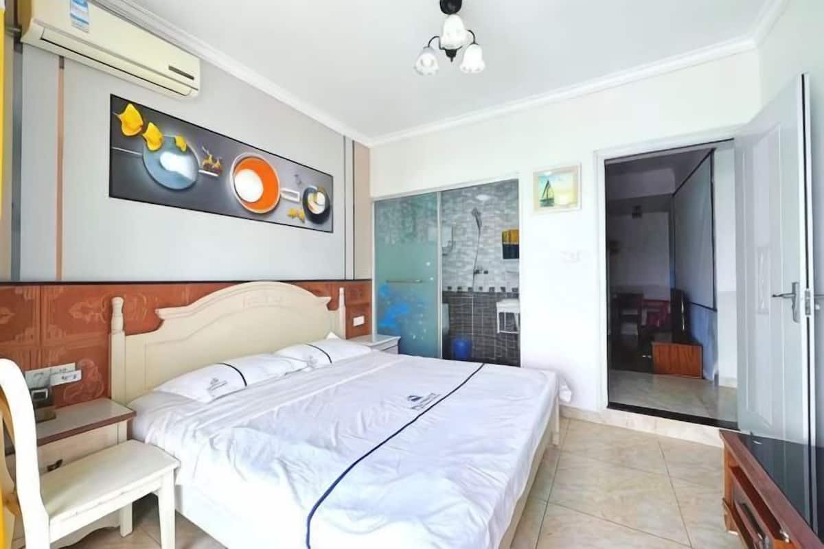 Een slaapkamer met een bed, een bureau en een stoel. Er is een deur die naar een andere kamer leidt.