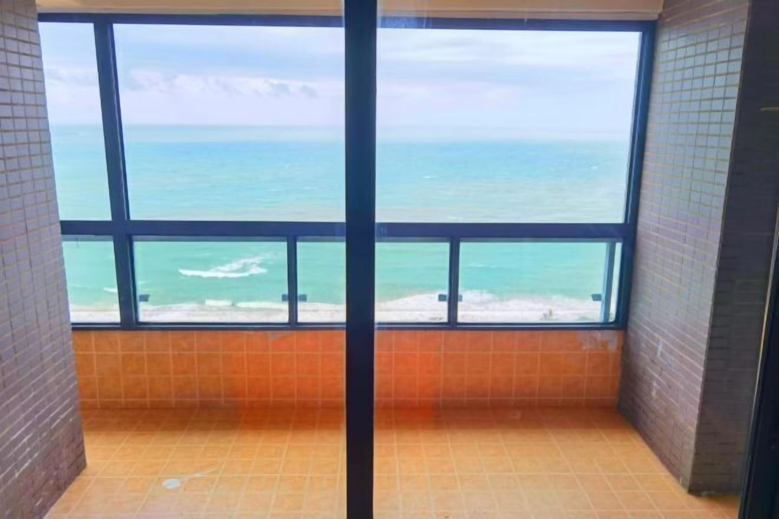 A room with a large window offering a view of the ocean.