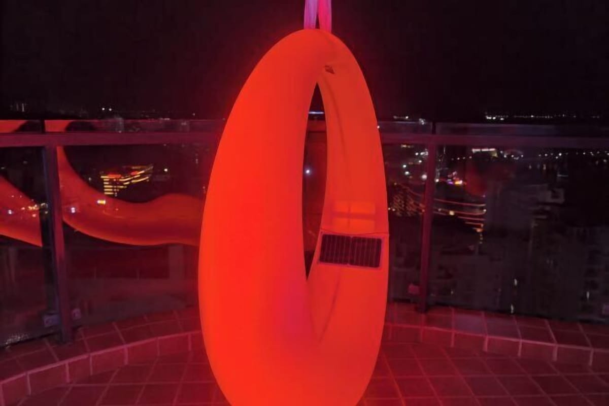 Una gran estructura circular roja e iluminada en un entorno urbano durante la noche.
