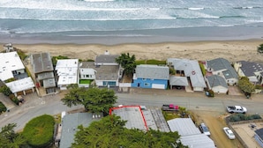 Vista aérea de uma área residencial costeira com casas, uma praia e uma estrada.
