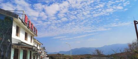 A street with buildings, a clear sky, and distant mountains.