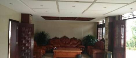A spacious living area with a large wooden sofa, a coffee table, and potted plants.