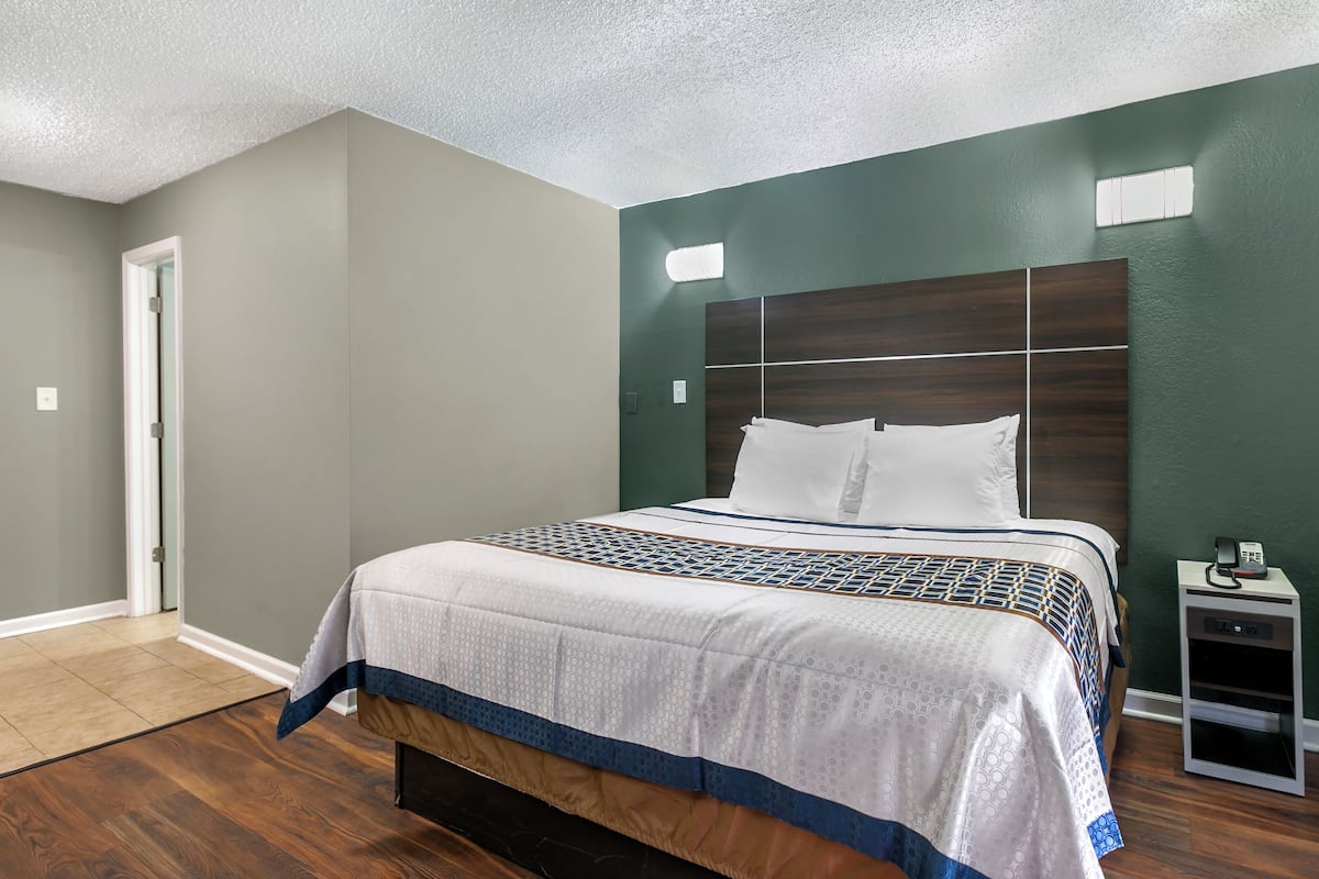 A bedroom with a large bed, a nightstand, and a door.