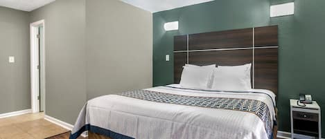 Une chambre à coucher avec un grand lit, une table de chevet et une porte.