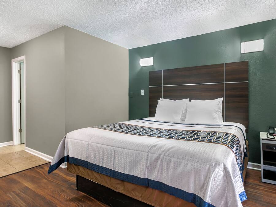 A bedroom with a large bed, a nightstand, and a door.