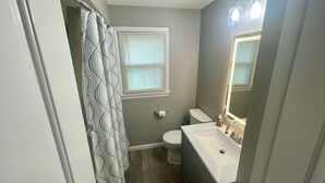 A compact bathroom with a toilet, sink, and shower.