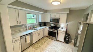A modern kitchen with white cabinets, a stainless steel stove, a microwave, and a dishwasher.