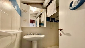 A bathroom with a pedestal sink, a bathtub, and a mirror with a starfish decoration. - Casa Petralana by Wonderful Italy (Olbia)