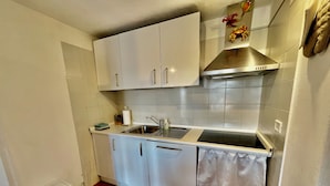 A compact kitchen with white cabinets, a stainless steel sink, and a tiled backsplash. - Casa Petralana by Wonderful Italy (Olbia)