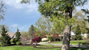 A well-maintained lawn with a large tree and a flower bed. - Huge house for large groups! Basketball court, arcade, putting green.4 bathroom (Machesney Park)