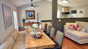 A dining area with a wooden table, patterned chairs, a sofa, and a kitchen in the background. - Huge house for large groups! Basketball court, arcade, putting green.4 bathroom (Machesney Park)