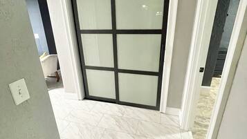 A hallway with a sliding glass door leading to a room with a tiled floor.