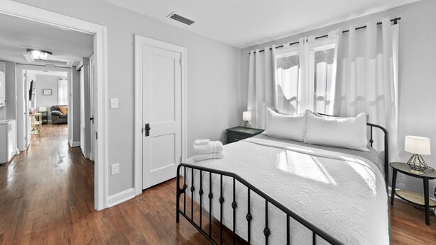 A bedroom with a bed, a nightstand, a lamp, and a view of the hallway. - Sunny Side Murry Hill Home (Jacksonville)