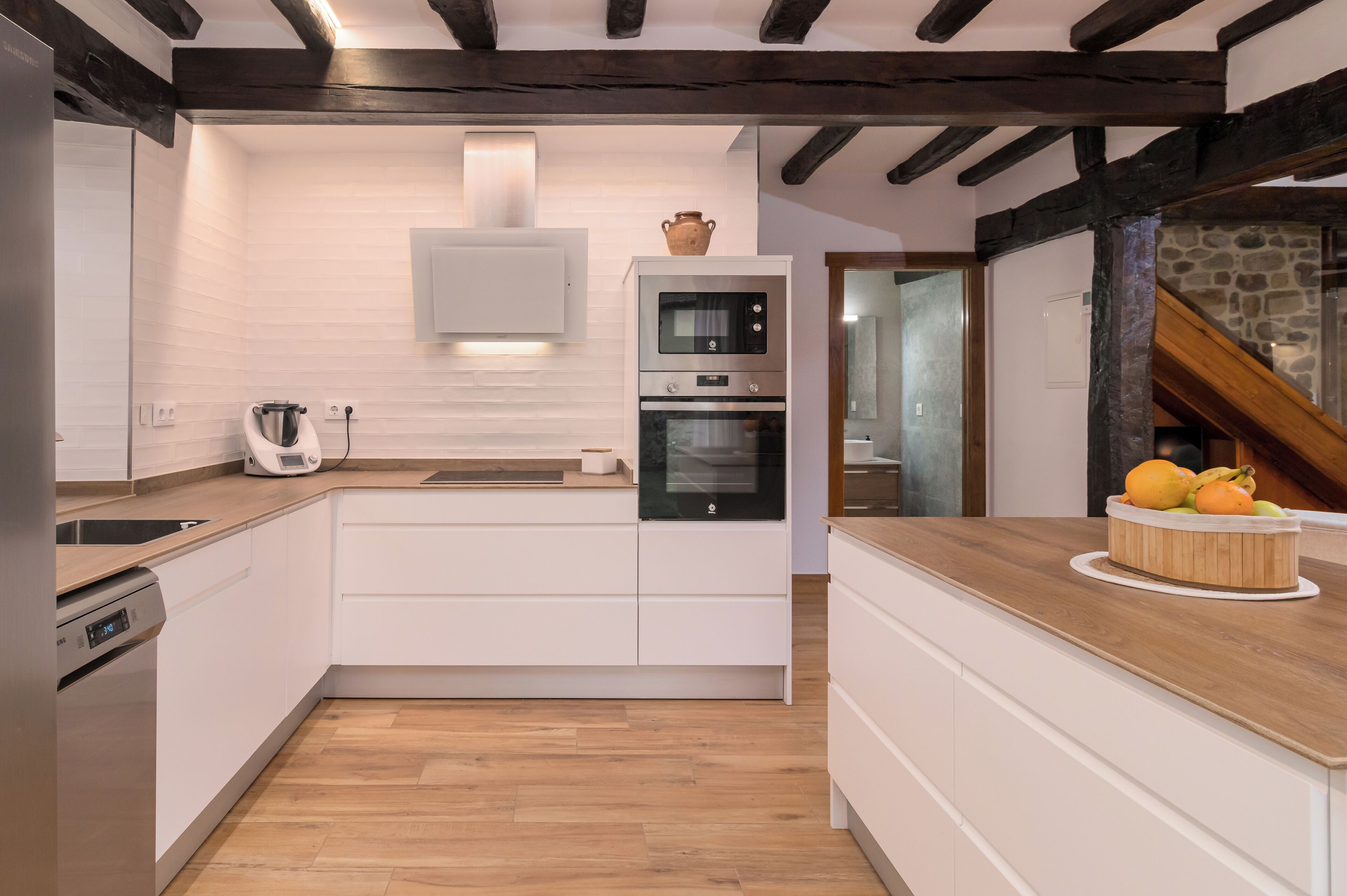 A modern kitchen with white cabinetry, wooden countertops, and a built-in oven.