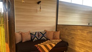 A modern room with a dark sofa, patterned pillows, and a wooden accent wall. - Luxury Glamping in Ruztico (Villavicencio)
