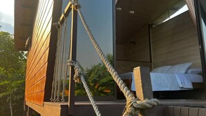 A modern cabin with a large window, a rope ladder, and a bed visible inside. - Luxury Glamping in Ruztico (Villavicencio)