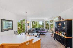 Amplia sala de estar con una mesa de comedor, sillas, un sofá y un mueble negro con adornos.