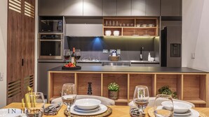 Una cocina moderna con electrodomésticos integrados, armarios de madera y una zona de comedor con mesa dispuesta para cuatro personas.