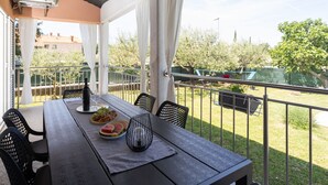En balkon med et spisebord, der viser en flaske, vinglas og en tallerken med mad.