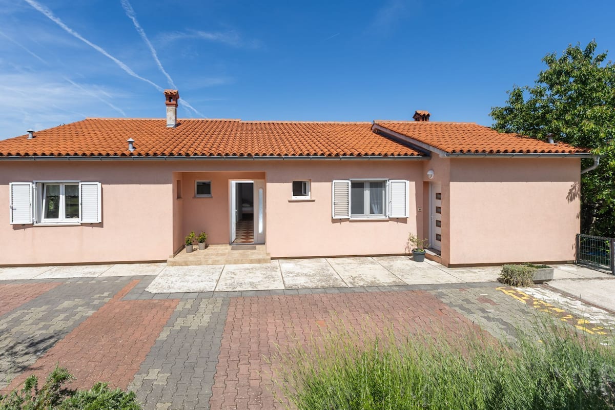 A single-story building with a red-tiled roof, a front door, and a small porch area.