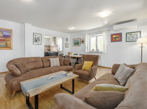 A living room with a sofa set, a dining table, and a kitchen in the background. - Villa Sabina - Breg Ivanovci (Labin)