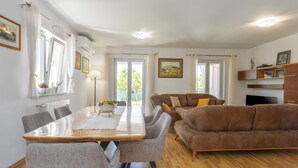 En moderne stue med et træspisebord, grå stole, en brun sofa og et fjernsyn.
