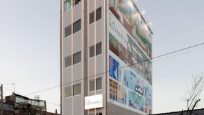 A tall hotel with a large mural on its side, multiple floors, and a sign indicating it is a hotel. - La Hospedería León (León)