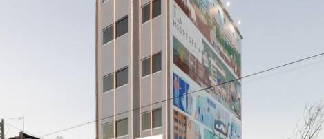 A tall hotel with a large mural on its side, multiple floors, and a sign indicating it is a hotel.