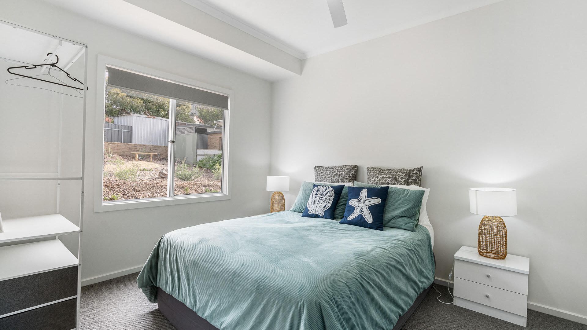 A bedroom with a bed, bedside tables, a window, and a wardrobe.