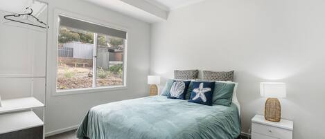A bedroom with a bed, bedside tables, a window, and a wardrobe.