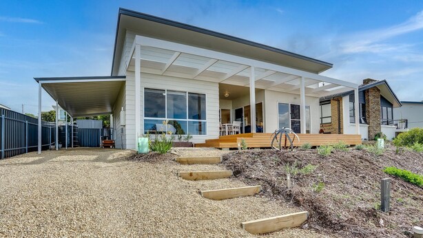 A modern two-story house with a covered patio, large windows, and a well-maintained garden.