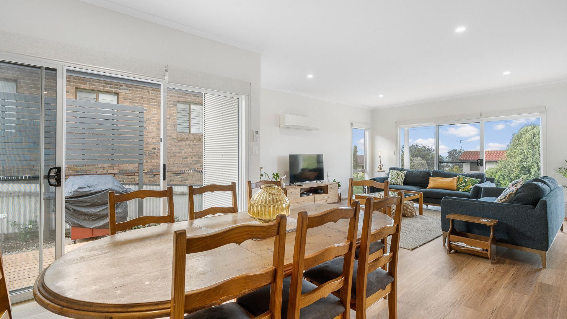 Una sala de estar moderna con comedor, ventanas grandes y televisor.