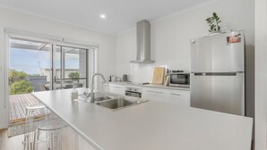 A modern kitchen with a large island, stainless steel appliances, and a view of the outdoors.