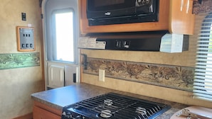 Une cuisine compacte équipée d’une cuisinière, d’un four à micro-ondes et d’un petit réfrigérateur.