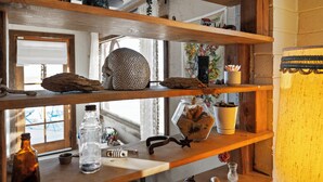 Una estantería de madera con diversos objetos, como un tarro de vidrio, una escultura de metal y una planta en maceta.