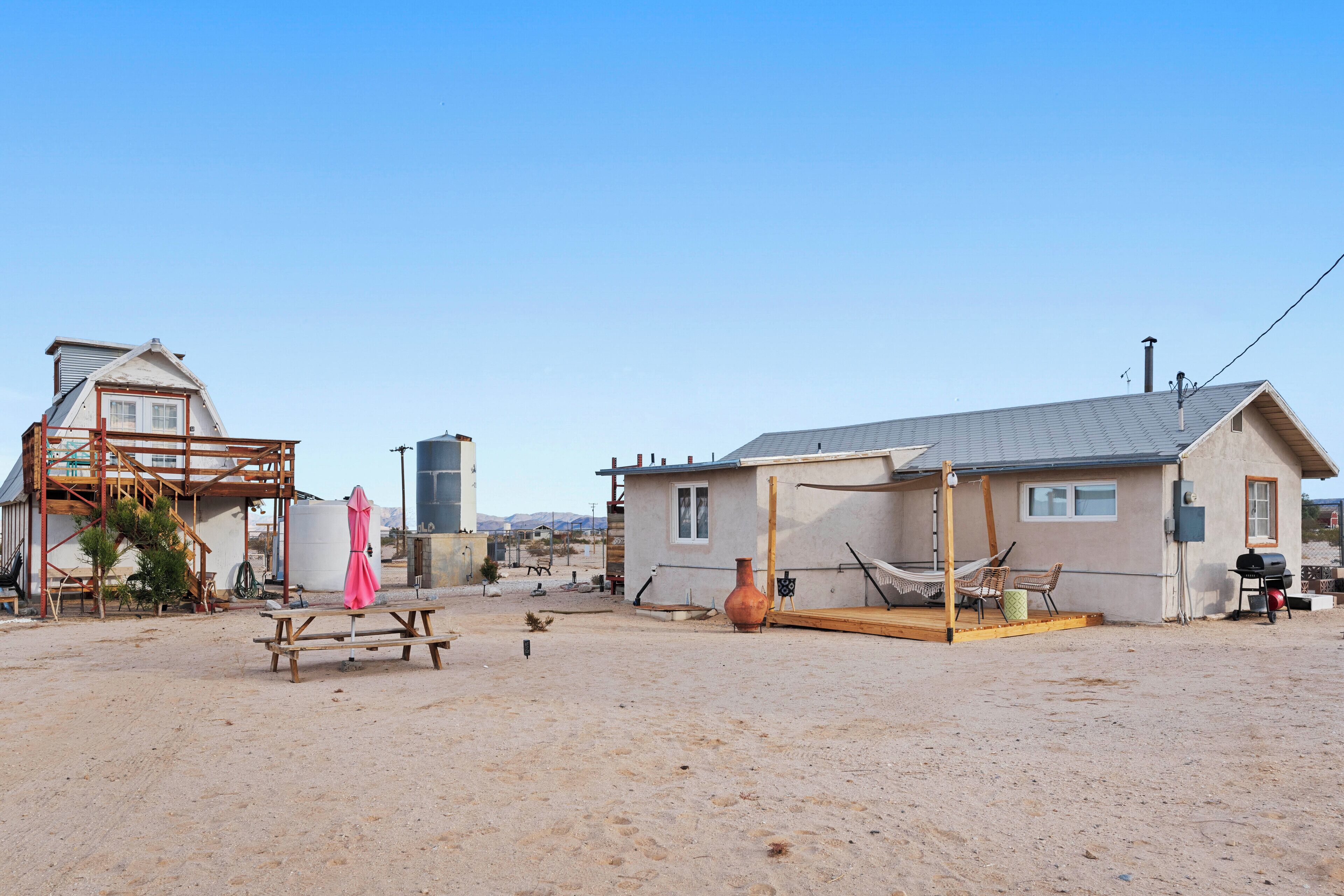 A desert-style house with a wooden deck, a hammock, and a barbecue area.
