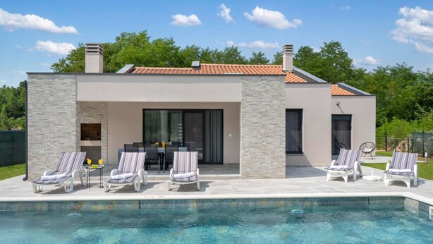 Een modern huis met zwembad, stenen gevel en een terras.