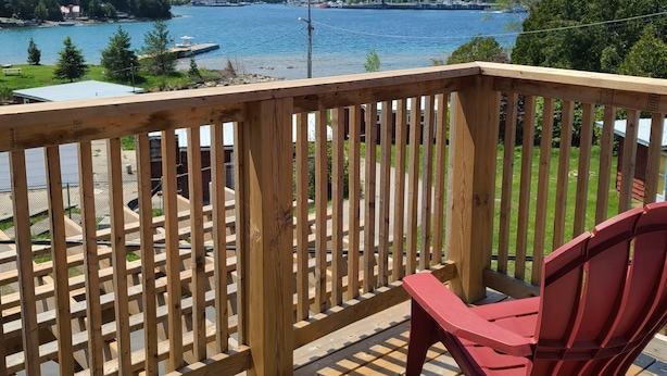 Un terrazzo in legno con vista su un lago e edifici in lontananza.